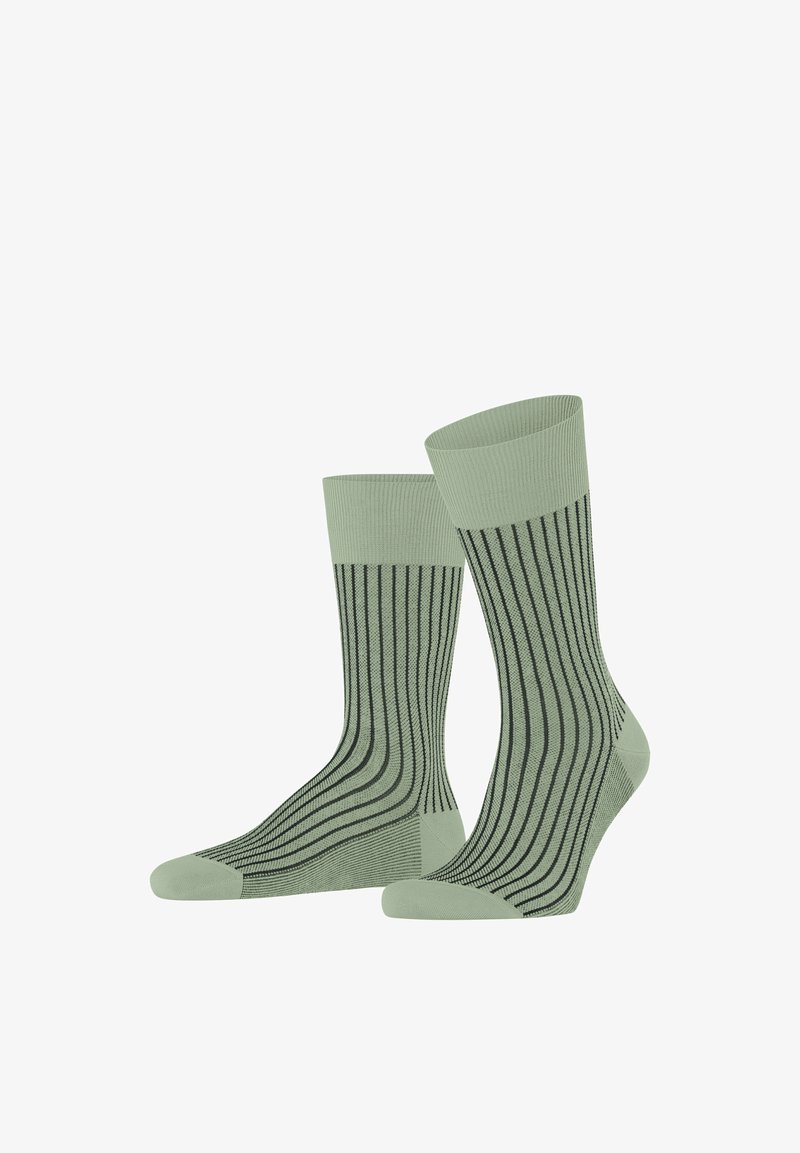 Paar hellgrüne Socken mit dunklen vertikalen Streifen, gerippten Bündchen sowie verstärkten Zehen und Fersen, auf weißem Hintergrund aufrecht stehend präsentiert.