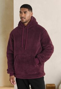 Bordeaux fleece hoodie met een voorkant vak, verstelbare trekkoordkap en ribbelboorden. Zachte textuur en een relaxte pasvorm.