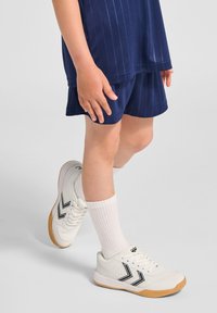 Koszulka w paski w kolorze granatowym, granatowe szorty, białe buty sportowe z czarnymi akcentami i białe skarpetki; lekki materiał i sportowy krój.