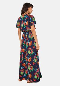 Robe maxi en tissu bleu marine avec un motif floral éclatant mettant en valeur des accents rouges, orange et verts. Manches fluides et taille élastique.
