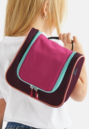Lila und rosa Rucksack mit strukturiertem Design, ausgestattet mit einem türkisfarbenen Reißverschluss und zwei Reißverschluss-Ziehplatten, auf dem Rücken getragen.