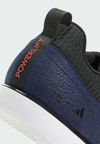 Námořnická tréninková obuv s texturovaným povrchem, černými akcenty a červeným logem "POWERLIFT". Bílá podrážka s vzorovaným protiskluzovým detailem.