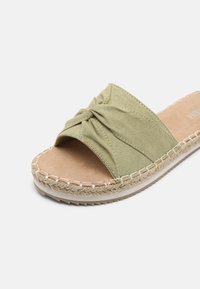 Green suede slide sandal with a knotted design on the strap, jute-wrapped sole, and a cushioned footbed. Flat, open-toed style.