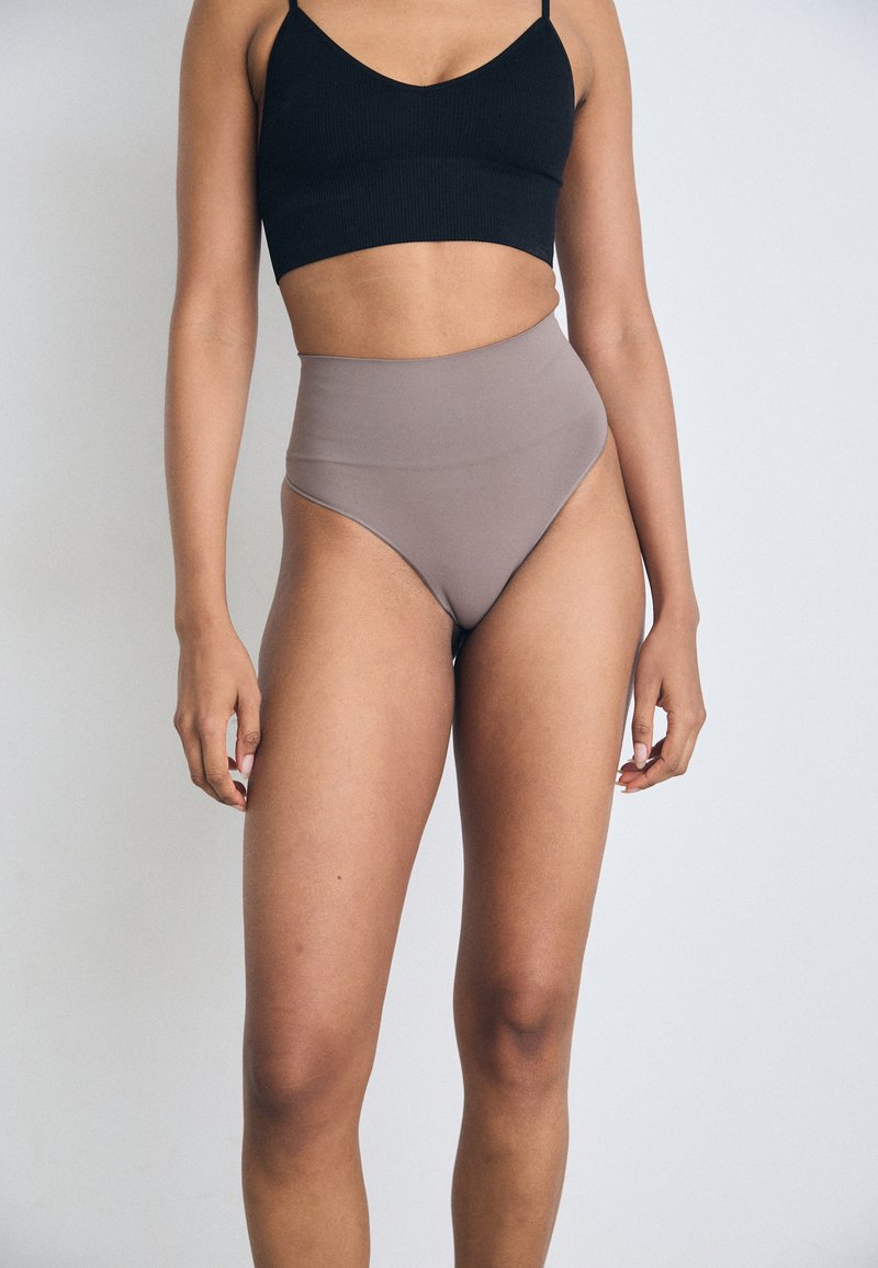 Slip da bagno marroni a vita alta realizzati in tessuto liscio, caratterizzati da un design elegante con cuciture minime e un'apertura per le gambe curva.
