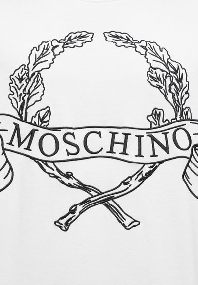 Λευκό μπλουζάκι με μαύρο περίγραμμα γραφικού στεφάνι δάφνης με δύο σταυρωτά κλαδιά και κορδέλα που απεικονίζει τη λέξη "MOSCHINO" με έντονα γράμματα.