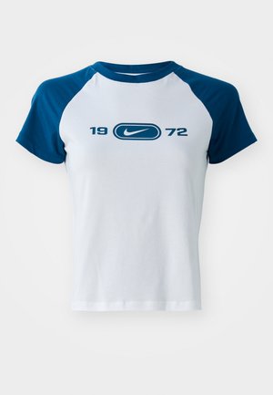 Balts kokvilnas T-krekls ar ziliem raglanu piedurknēm, centrā ar logo un zem tā drukātu "1972" zilā krāsā. Īsas piedurknes un apaļa kakla izgriezums.