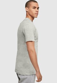 Camiseta gris de cuello redondo hecha de una tela suave, con mangas cortas y un corte relajado. Sin patrones ni acentos visibles. Diseño simple y clásico.