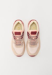 Light pink and burgundy sneaker with mesh and suede materials, cushioned sole, patterned laces, and logo patch on the tongue.