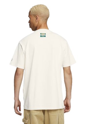 Witte t-shirt met korte mouwen, een ronde hals en een klein groen label op de achterkant. De stof lijkt zacht en lichtgewicht te zijn.