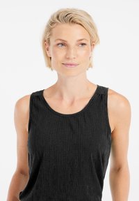 Top senza maniche nero in tessuto strutturato con scollo rotondo e ampie aperture per le braccia, caratterizzato da dettagli di cucitura discreti sulle spalle.