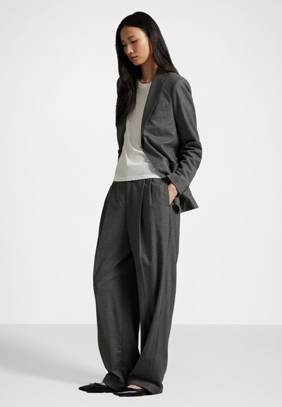 Gray tailored blazer and wide-leg trousers with a cream shirt. Blazer features notched lapels; pants have pleats and relaxed fit. Black slip-on shoes.
