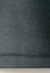 Tela de fieltro gris oscuro con una superficie ligeramente texturizada, que presenta un dobladillo cosido en la parte inferior. Diseño sencillo sin patrones destacados.