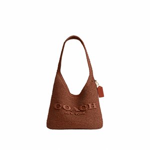 Brown woven Coach shoulder bag with wide strap and a small hanging tag on plain white background.