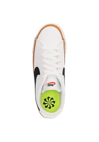 Zapatilla de cuero blanca con Swoosh negro, ribetes naranjas y plantilla verde con un diseño floral. Los cordones son blancos y tienen una lengüeta acolchada.