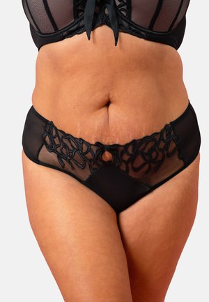Frau trägt schwarze transparente Unterwäsche mit bestickten Mustern und kleinem vorderem Ausschnitt an der Panty, gezeigt vom Bauch bis zu den oberen Oberschenkeln.