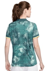 Polo shirt teal con texture stampata, dotata di maniche corte, una bordatura gialla al colletto e alle maniche, e un design geometrico alla moda.