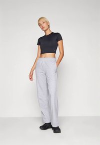 Črna športna kratka majica s kratkimi rokavi in sive široke športne hlače z elastičnim pasom in mehko teksturo.