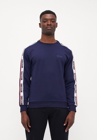 Sweatshirt bleumarin cu mâneci lungi, cu dungi laterale albe contrastante și branding "MOSCHINO". Fabricat dintr-un amestec de bumbac, design cu guler rotund.