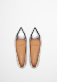 Chaussures plates métalliques argentées avec un design à bout pointu et une finition lisse. L'intérieur présente une semelle intérieure beige avec des détails de logo.