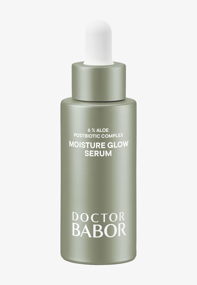 Bottiglia di siero in vetro verde con tappo contagocce bianco. L'etichetta riporta "Complesso Postbiotico di Aloe al 6%" e "Siero Idratante Luminoso" in testo bianco.