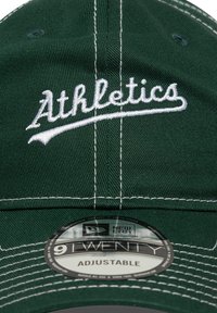Green adjustable cap with white embroidered "Athletics" logo, featuring white stitching and a circular New Era label on the brim.