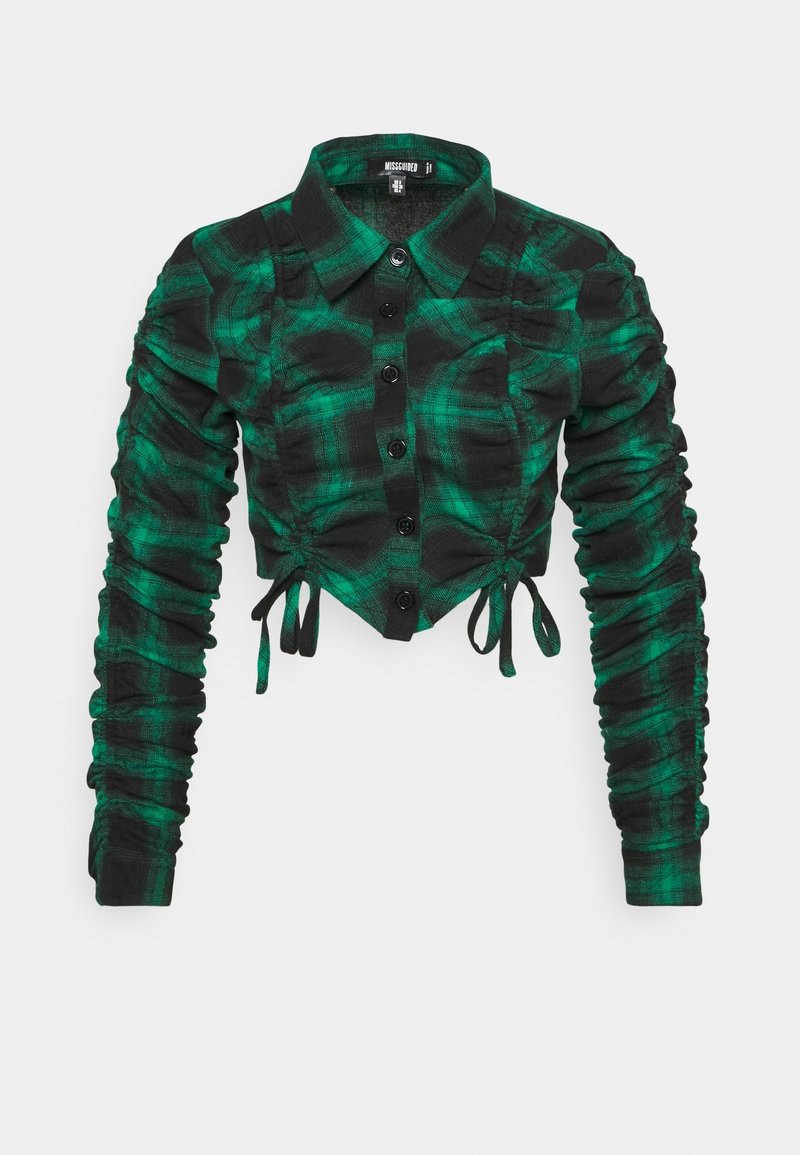 Camicia corta a quadri verdi e neri con un davanti bottonato, maniche lunghe arricciate e dettagli a lacci in vita e sulle maniche.