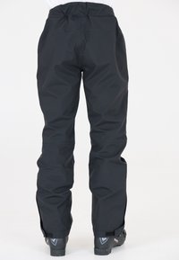 Pantalons de ski noirs imperméables avec taille élastique et jambes fuselées, dotés de poignets aux chevilles en velcro et d'une texture lisse et brillante.