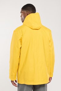 Veste imperméable jaune avec capuche, présentant une texture lisse et une coupe décontractée. Le dos affiche de simples détails de couture.