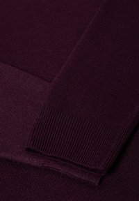 Tejido de suéter burdeos con puños acanalados y textura suave, que presenta un brillo sutil y bordes limpios.