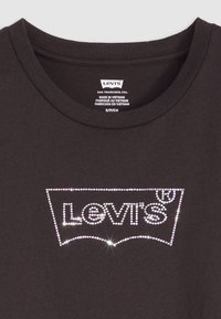 T-shirt in cotone nero con logo Levi's in strass dal design curvo, con una texture liscia e un classico scollo rotondo.