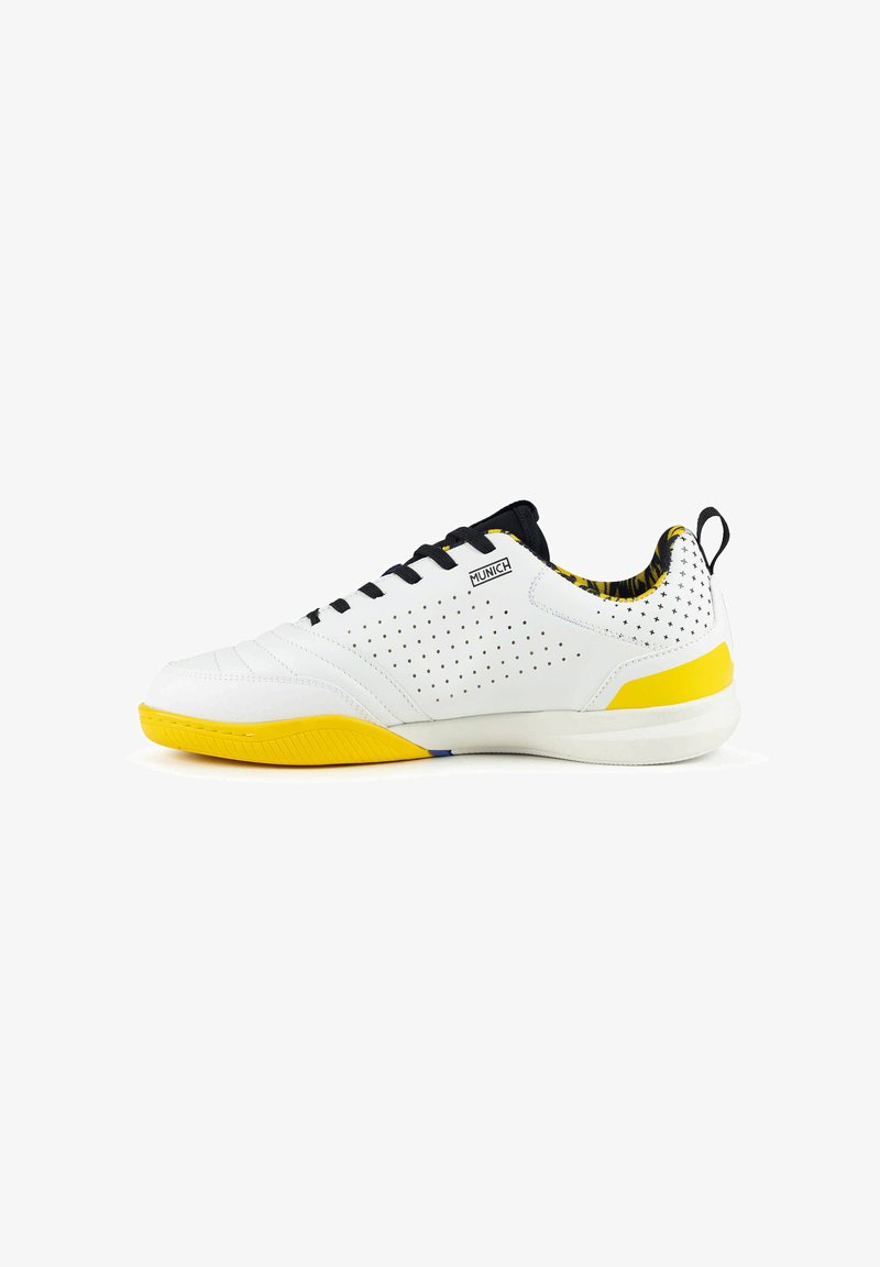 Chaussure de sport blanche et jaune avec lacets noirs, côté perforé, doublure intérieure à motifs et languette au talon.