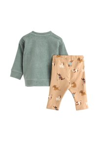 To-delt børnetøj: grønna corduroy sweater med ribbet tekstur og beige leggings med et gentaget hundemønster i forskellige farver.