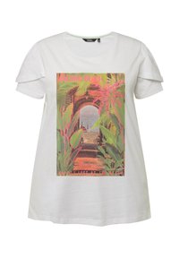 T-shirt bianca a maniche corte con una grafica colorata che include piante tropicali e testo, ambientata in una scena di spiaggia.