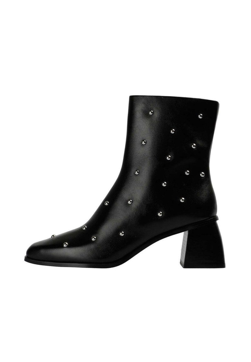 Bota tobillo de cuero negro con punta puntiaguda, decorada con tachuelas plateadas y un tacón grueso de bloque. Textura suave y diseño elegante.