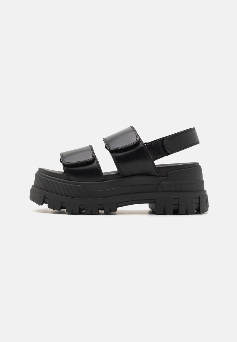 Black platform sandals featuring two wide straps with Velcro closures. Chunky rubber sole with ridged traction pattern and open back design.