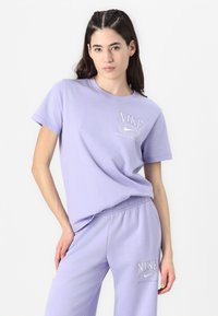 Lila Nike t-paita ja siihen sopivat verkkarit, valmistettu pehmeästä puuvillasta, jossa on valkoinen logo painatus rinnassa ja lahkeessa.