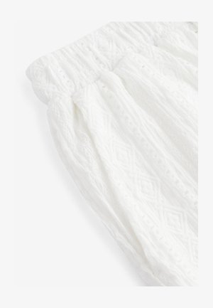 Vitt strukturerat tyg med ett diamantsmönster. Elastisk midja med rynkdetaljer. Lätt och luftigt material som passar för varma väderförhållanden.