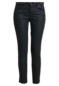 Pantalones negros ajustados con una cintura alta y un patrón de lunares negros, con bolsillos frontales y cierre de botón.
