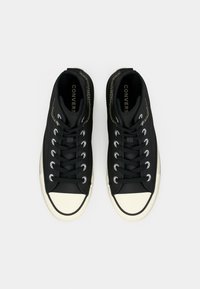 Sneakers nere alte con punta in gomma bianca e occhielli, caratterizzati da una tomaia testurizzata e cuciture decorative lungo la caviglia.
