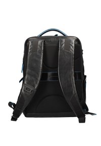 Zaino in pelle nera con retro in rete testurizzata, spallacci regolabili e dettagli in cerniera blu. Presenta un design strutturato e rettangolare.