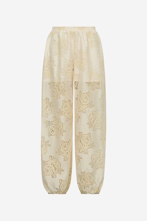 Cremefarbene Spitzenhose mit Blumenmuster, elastischem Bund und gerafften Bündchen auf weißem Hintergrund.