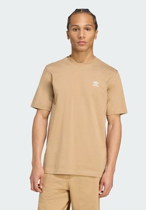 Tan kleur katoen t-shirt met een ronde hals, korte mouwen en een klein wit Adidas-logo op de linkerborst. Gladde textuur, relaxte pasvorm.