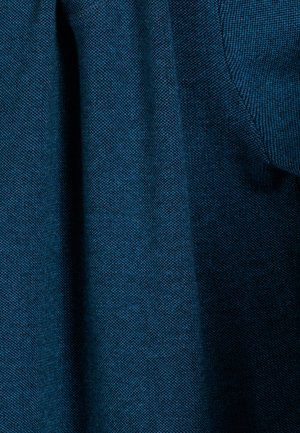 Textured fabric in a deep teal color, showcasing a woven pattern. The material has a soft, breathable quality with slight sheen.