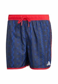 Kąpielówki z niebieskim geometrycznym wzorem, elastyczną talią z czerwonym sznurkiem i czerwonym wykończeniem. Zawierają logo Adidas na dolnym brzegu.