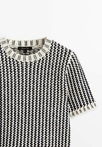 Kortærmet skjorte i sort og creme med zigzag-mønster. Ribbet rund hals og struktureret stof. Letvægts- og åndbart design.