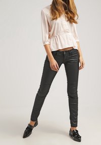 Różowa bluzka z marszczeniem w talii i rękawami 3/4, zestawiona z czarnymi dżinsami skinny i czarnymi mokasynami. Gładkie faktury.