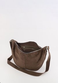 Brun ruskinds skuldertaske med en buet form, lynl�ås lukning og en justerbar rem. Indvendigt har den en lynlås lomme og stofforing.