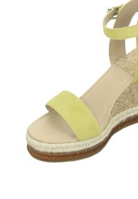 Yellow suede sandal featuring a wide strap, a beige insole, and a woven jute platform with a textured brown rubber outsole.