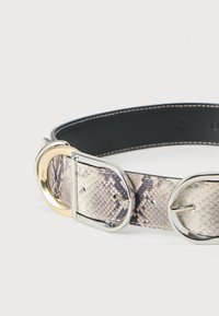 Ζώνη με μοτίβο πύθωνα σε δίχρωμο σχέδιο, με ασημί αγκράφα και χρυσή λεπτομέρεια. Λεια υφή, μαύρη πίσω πλευρά και λεπτή ραφή.