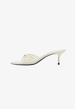 Mule beige à bout ouvert avec talon stiletto et fines lanières courbées à l'avant.